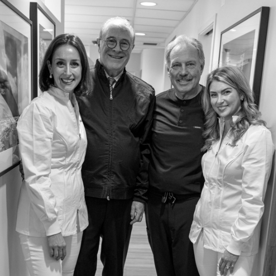 Four smiling prosthodontists in dental office hallway
