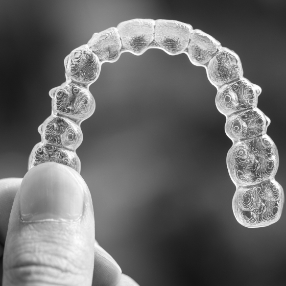 Hand holding an Invisalign clear aligner