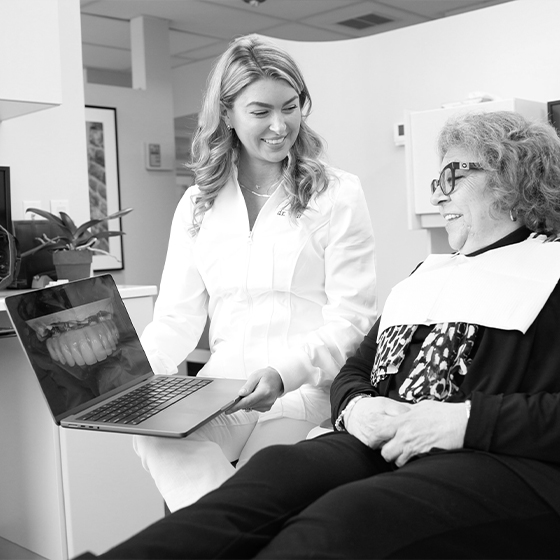 Dentist showing a patient a laptop showing model of implant denture