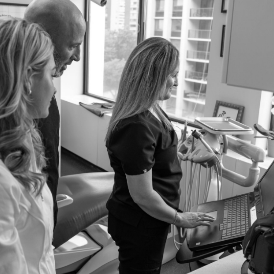 Three dental professionals looking at computer screen