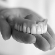 Person holding a complete denture in their hand