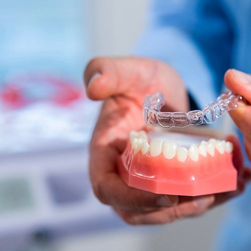 Dentist using model to demonstrate how Invisalign works