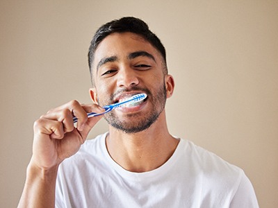 Man in white t-shirt brushing teeth