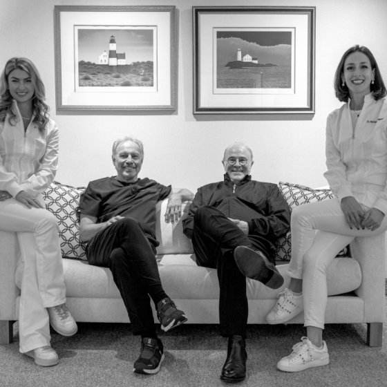 Four smiling Boston dentists sitting on couch