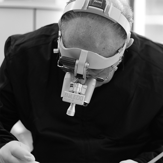 Dentist wearing dental binoculars while treating a patient