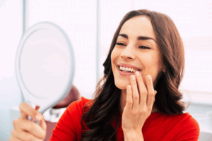 Woman examining her teeth in a small mirror