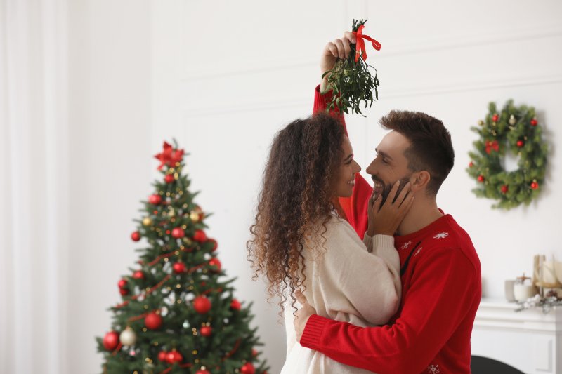 Couple with good oral hygiene smiling under the mistletoe 